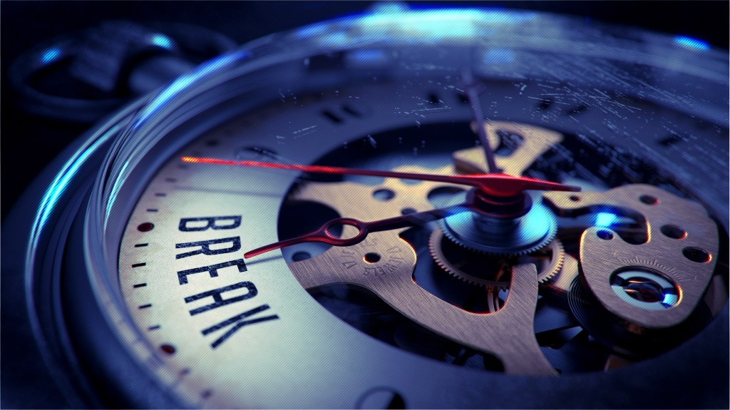 Close-up of a clock mechanism featuring the word 'BREAK' prominently displayed, with intricate gears and red clock hands.
